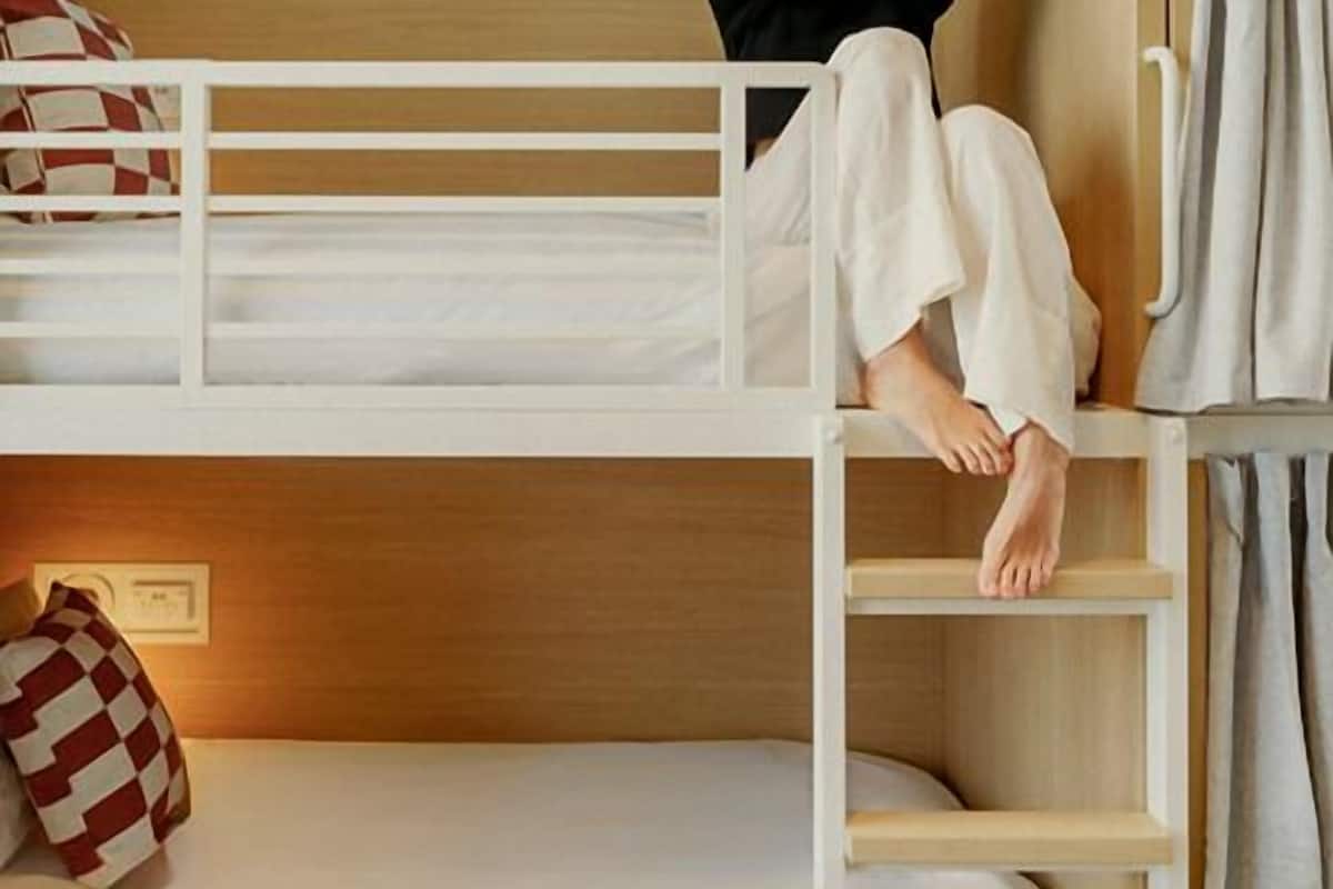 Una cama litera con escalera, un almohadón y una mesita de noche.