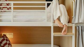 A bunk bed with a ladder, a pillow, and a bedside table.