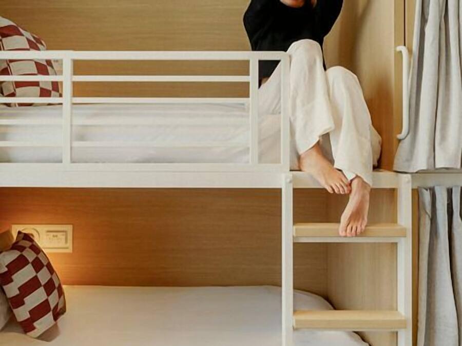 A bunk bed with a ladder, a pillow, and a bedside table.