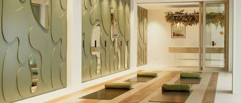 Un spa moderno con suelo de madera, asientos acolchados verdes y una amplia pared de espejos.