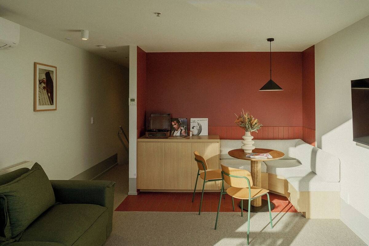 Un espacio habitable compacto con kitchenette, comedor y zona de estar con sofá y sillas.