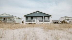 Una casa frente a la playa con un balcón y una escalera que lleva a la entrada.