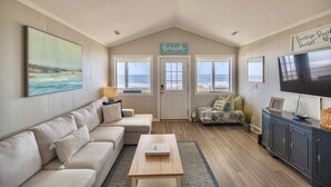 Una sala de estar con un sofá color crema, una mesa de centro, un televisor y un letrero que dice "The Beach".