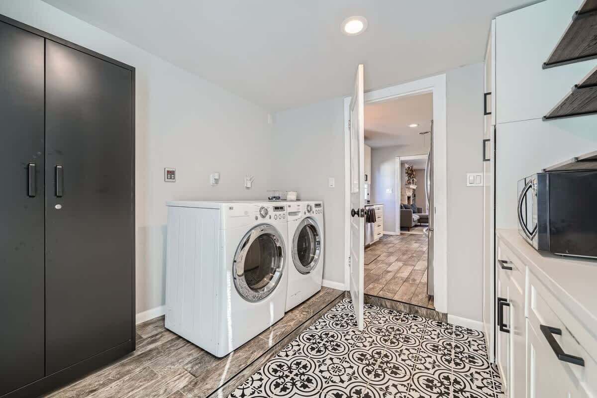 A laundry room with a washing machine and dryer, a dark cabinet, and a patterned floor.