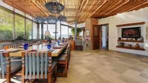 Un comedor con una larga mesa de madera, sillas y lámparas colgantes.