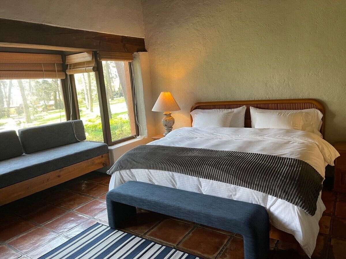 Een slaapkamer met een bed, een bankje en een raam.
