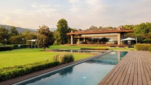 A swimming pool with a wooden deck, a lawn, and a building with outdoor seating. - El Salto: Luxury Ranch with Lake View (Valle de Bravo)
