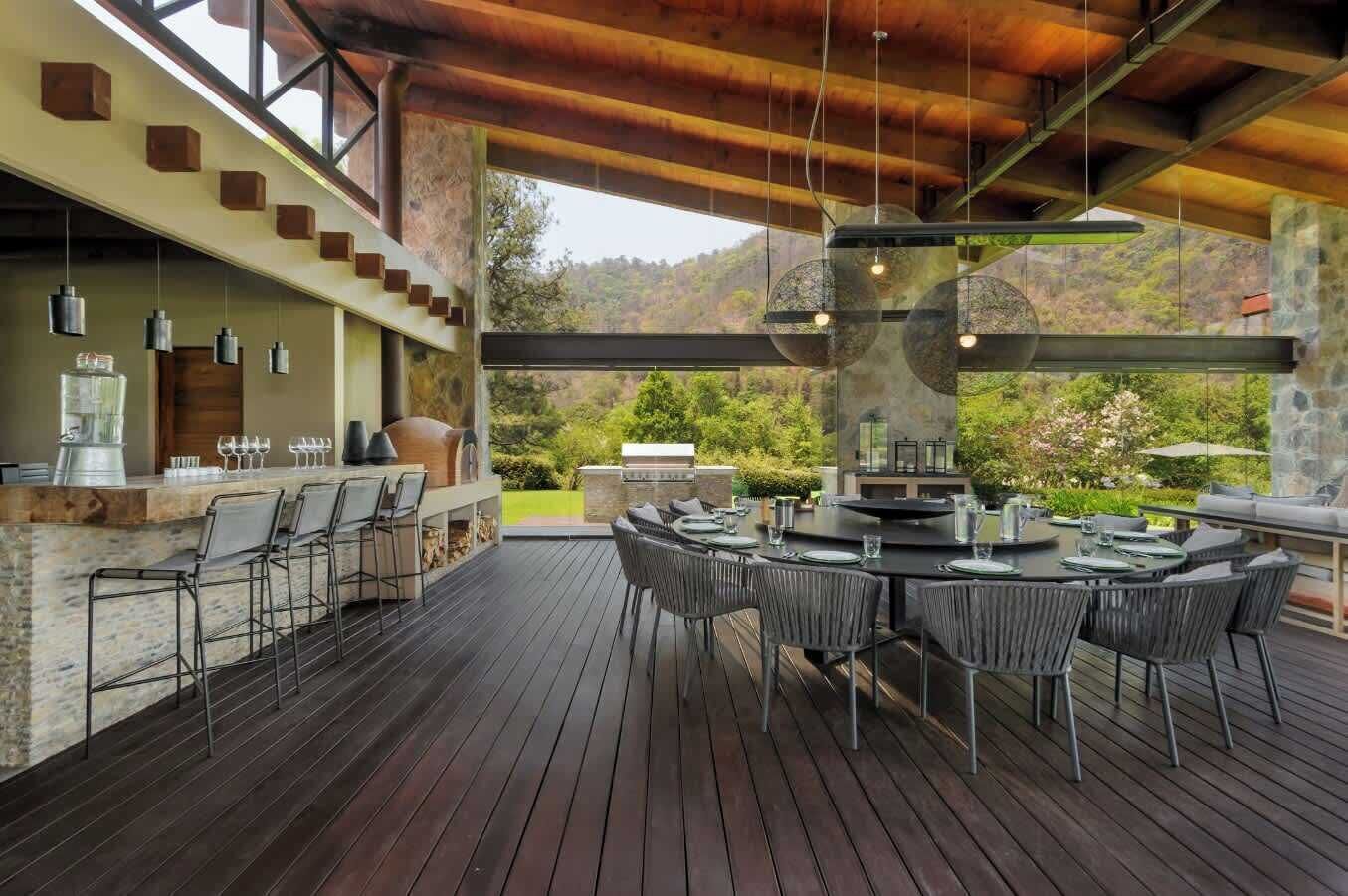 An outdoor dining area with a stone bar, multiple seating arrangements, and a view of the surrounding landscape.