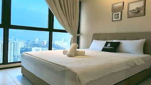 A hotel room with a large bed, a view of the city through floor-to-ceiling windows, and a pillow with a logo. - OYO Home 90948 Irishe Homestay Penang City Seaview (George Town)
