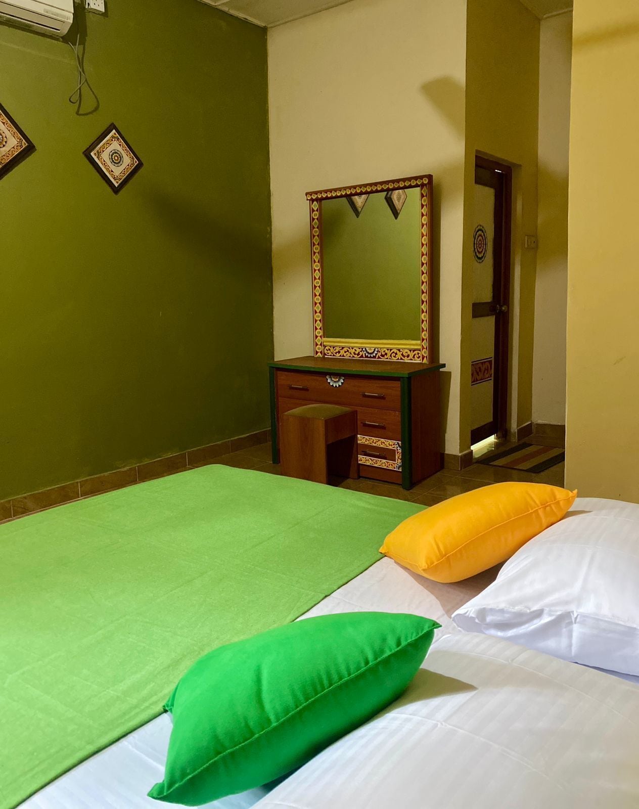 Una habitación con dos camas, un aparador de madera, un espejo y una puerta.