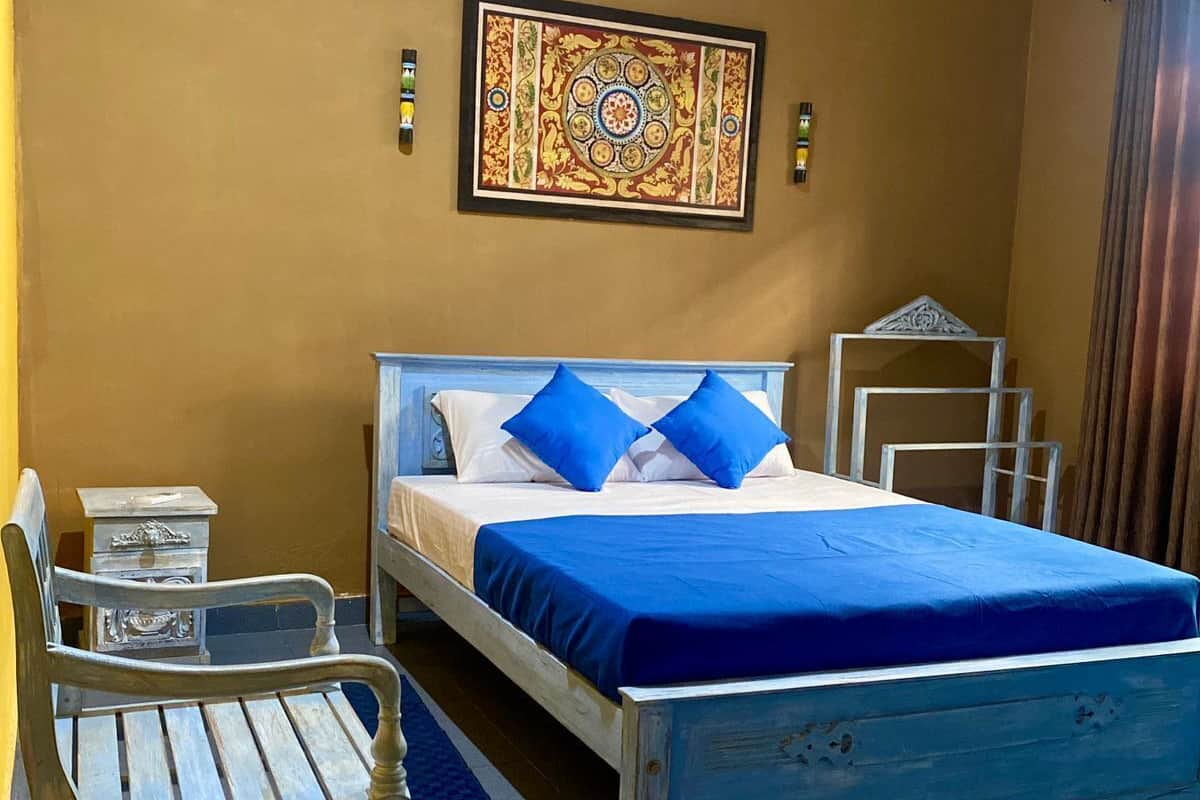 A bedroom with a bed, a chair, a nightstand, and a decorative wall piece.
