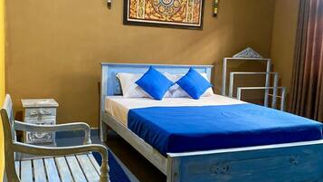 A bedroom with a bed, a chair, a nightstand, and a decorative wall piece.