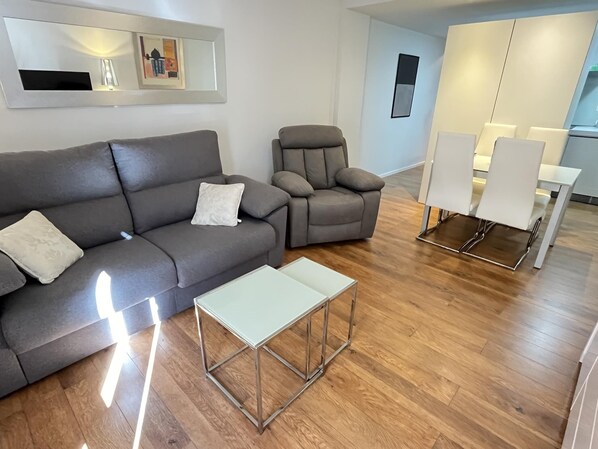 A modern living room with a grey sofa, a matching armchair, and a small white table. - Design flat in the historic centre of Denia (Dénia)