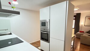 Une cuisine moderne avec des meubles blancs, un four encastré et un four à micro-ondes.