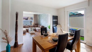 Ein Essbereich mit einem Holztisch, schwarzen Stühlen und Blick auf das Wohnzimmer.