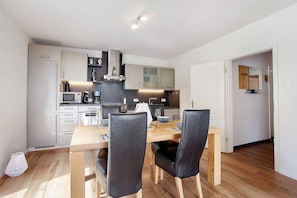 Una cocina moderna con armarios blancos, una mesa de comedor de madera y sillas negras.