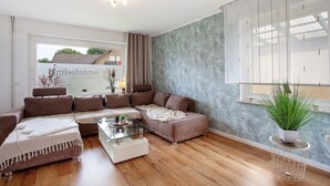 Ein modernes Wohnzimmer mit Ecksofa, Couchtisch und einer Zimmerpflanze.