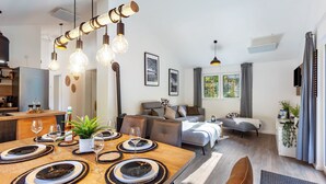 A modern living space with a dining area, sofa, and a kitchen in the background. - Vacation Home "14" with Private Terrace & Wi-Fi (Bad Arolsen)