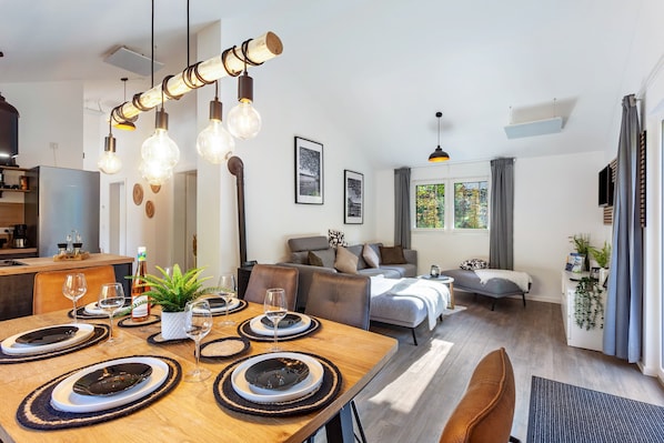 A modern living space with a dining area, sofa, and a kitchen in the background. - Vacation Home "14" with Private Terrace & Wi-Fi (Bad Arolsen)