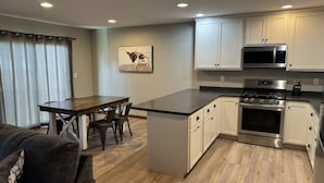 A modern kitchen with white cabinets, a stainless steel stove, and a microwave.
