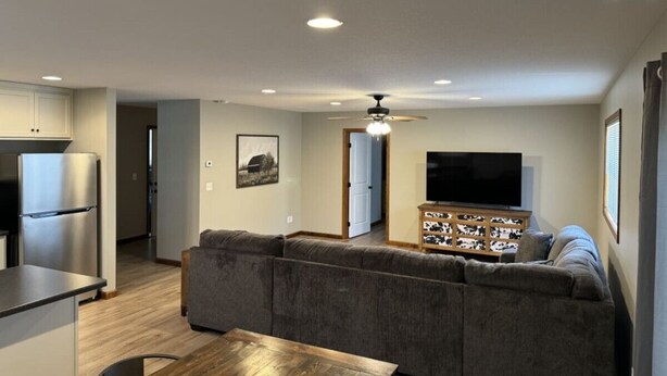 A modern living room with a grey sectional sofa, a wooden coffee table, and a TV on a wooden cabinet.