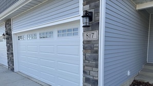 A house with a white garage door, stone pillar, and a house number 817.