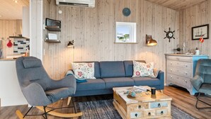Un salon chaleureux avec un canapé bleu, un fauteuil à bascule et une table basse en bois.