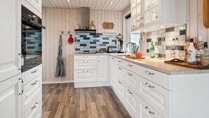 Une cuisine moderne avec des meubles blancs, un plancher en bois et un pare-feu en carrelage.