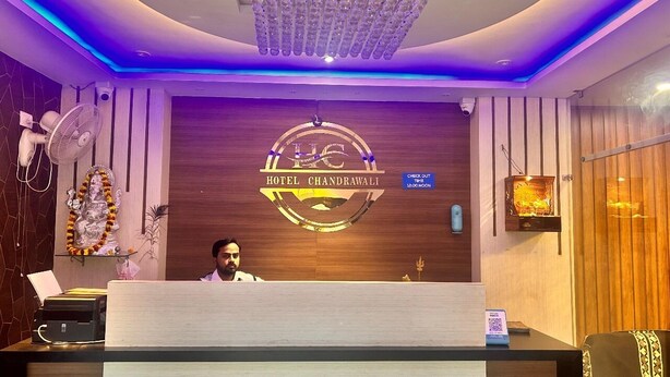 Una reception hotel con un logo, un bancone per il check-out, una ventola e una ghirlanda decorativa.