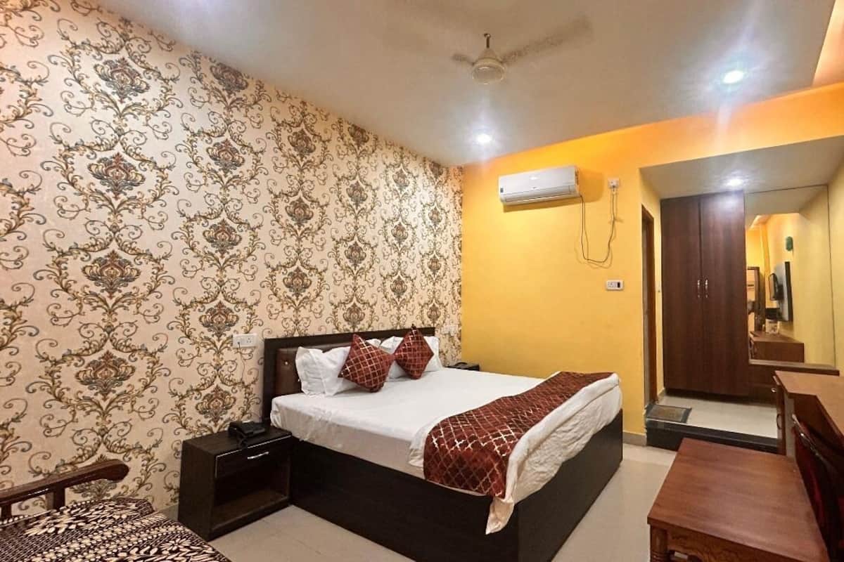 Une chambre à coucher comprenant un lit, des tables de chevet, un bureau, une chaise, un appareil de climatisation, un téléviseur et une armoire.