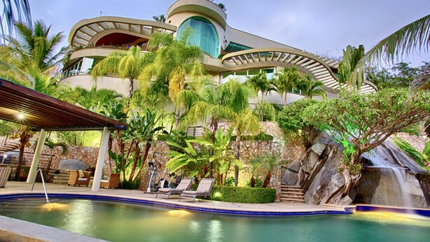 Een modern resort met een zwembad, ligbedden en een waterval.