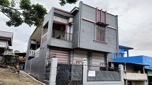 Un moderno edificio de dos pisos con entrada protegida por un portón, un balcón y el número 34 visible en la pared.