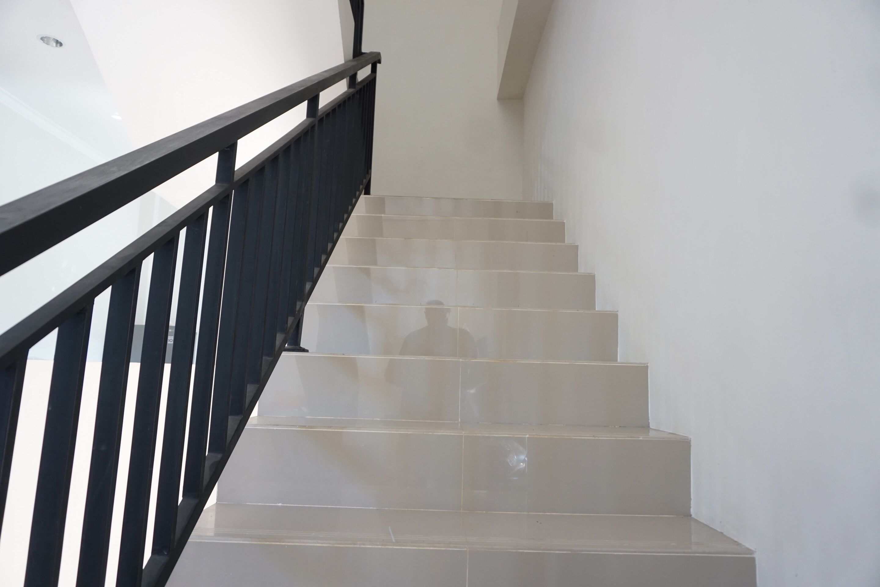 A staircase with a black railing and white walls.