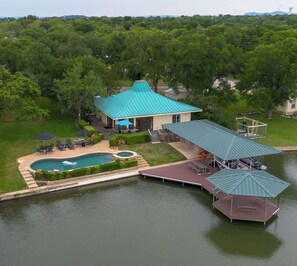 A house with a swimming pool, a dock, and a covered outdoor seating area.