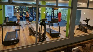 Une salle de sport équipée de divers appareils d’exercice, notamment des tapis de course, des vélos d’appartement et des appareils de musculation.