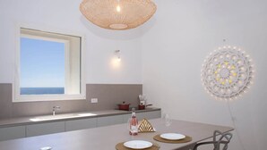 Een moderne keuken met een groot raam, een eettafel met twee stoelen en een decoratieve lamp aan de muur.
