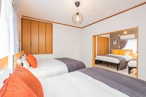 A bedroom with two beds, wooden wardrobes, a ceiling light, and a mirror. - ONCE Shinimamiya (Osaka)