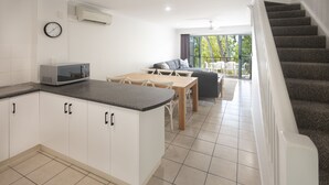 A modern kitchen with a dining area, a staircase, and a view of the outdoors.