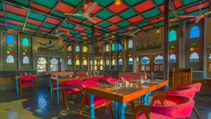 A restaurant with a high ceiling, colorful stained glass windows, and traditional Indian decor. - Aaj Haveli by Levelup (Udaipur)