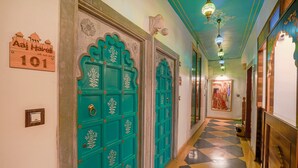 A hallway with turquoise doors, a checkered floor, and a sign indicating room number 101. - Aaj Haveli by Levelup (Udaipur)