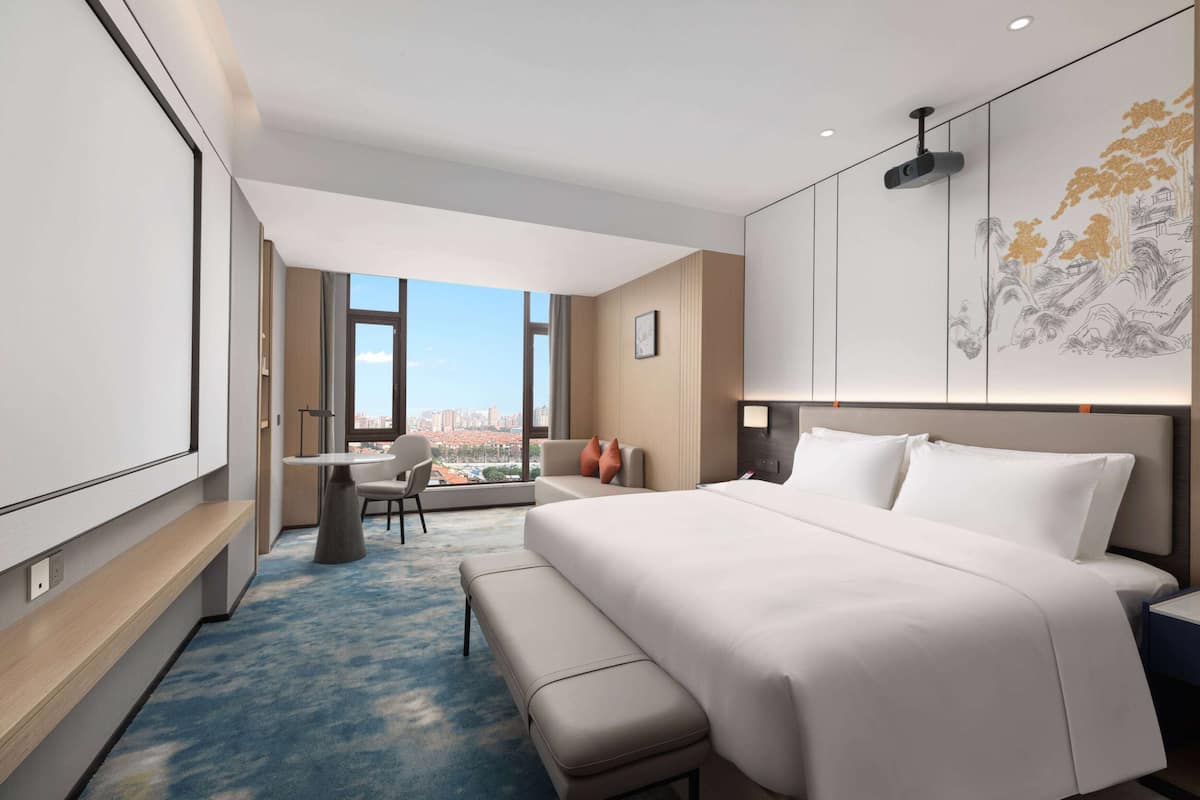 Een moderne hotelkamer met een groot bed, een bureau en uitzicht op de stad.