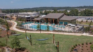 Un complexe hôtelier doté d’une piscine, de chaises longues et d’un bâtiment avec un patio couvert.
