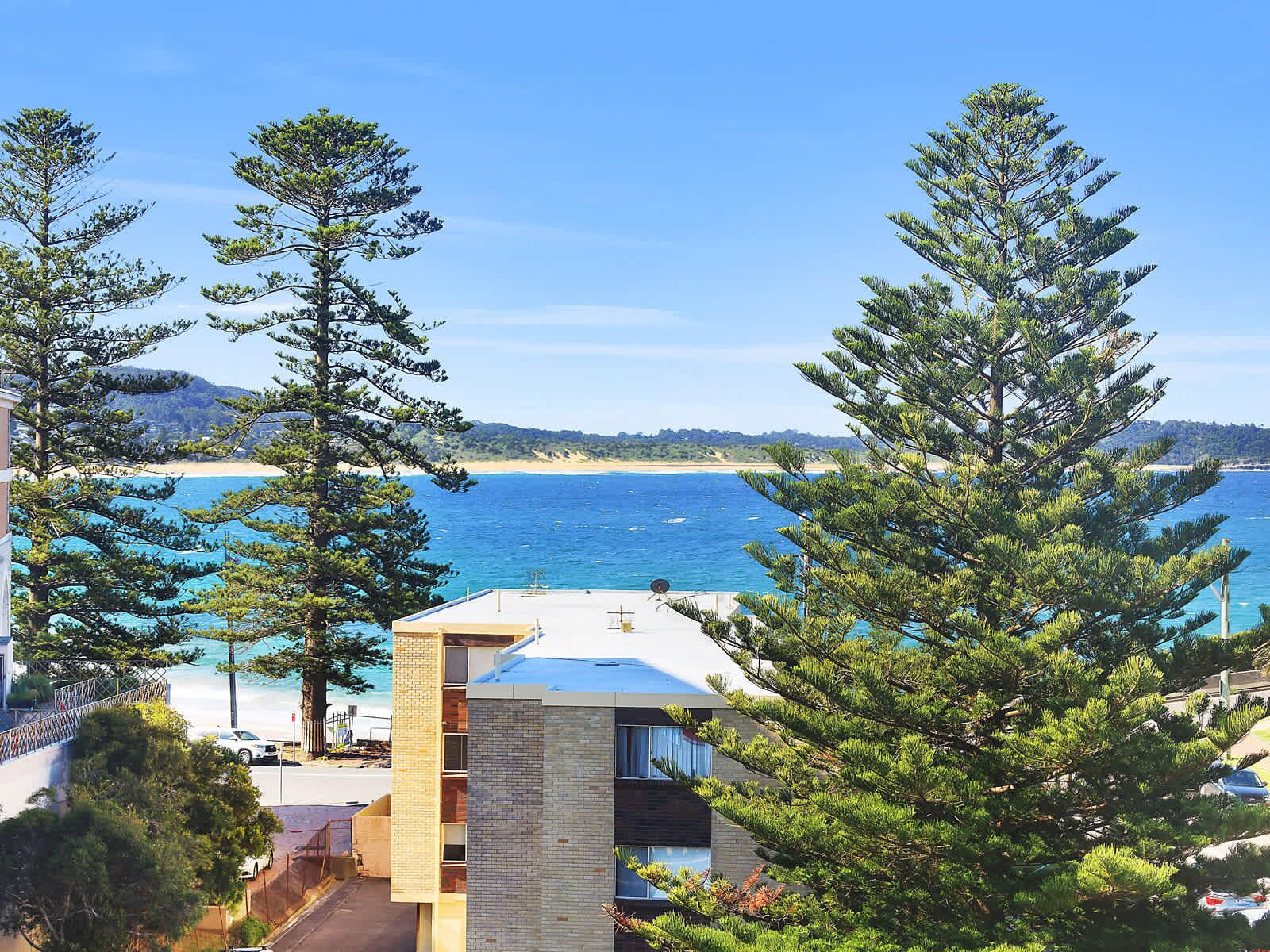 A modern building with a view of the sea and beach.