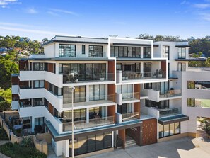 Un edificio residencial de varios pisos con balcones, ventanas amplias y techo plano.