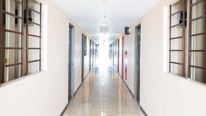 Un long couloir étroit, avec des portes de chaque côté, menant à des pièces individuelles.