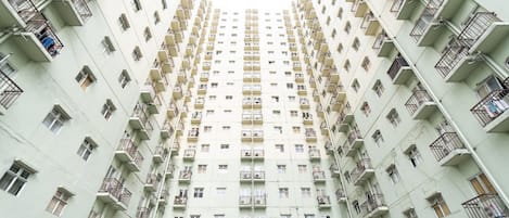 Un edificio residencial alto con múltiples balcones y unidades de aire acondicionado.
