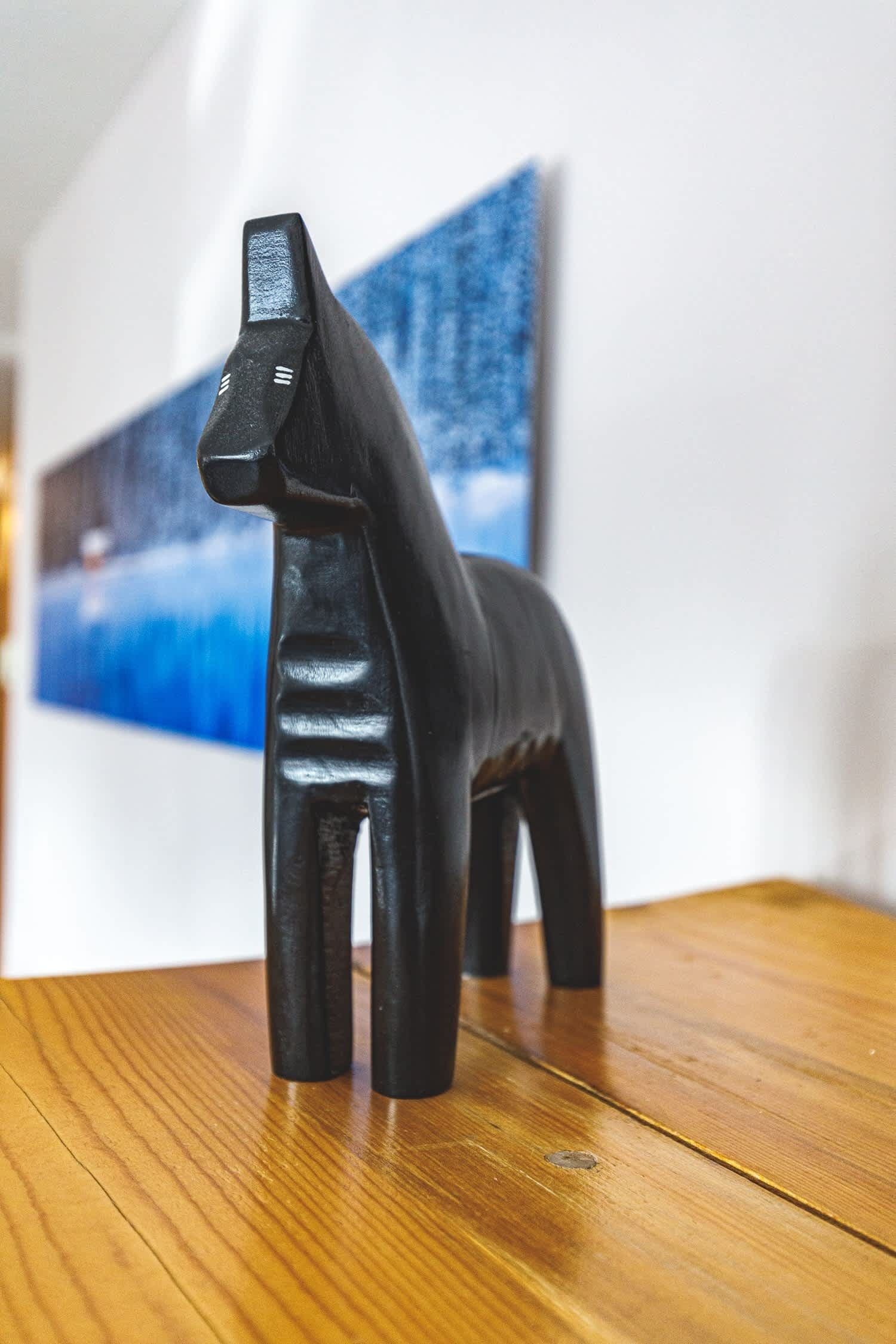 Une sculpture représentant un cheval noir, posée sur une surface en bois.