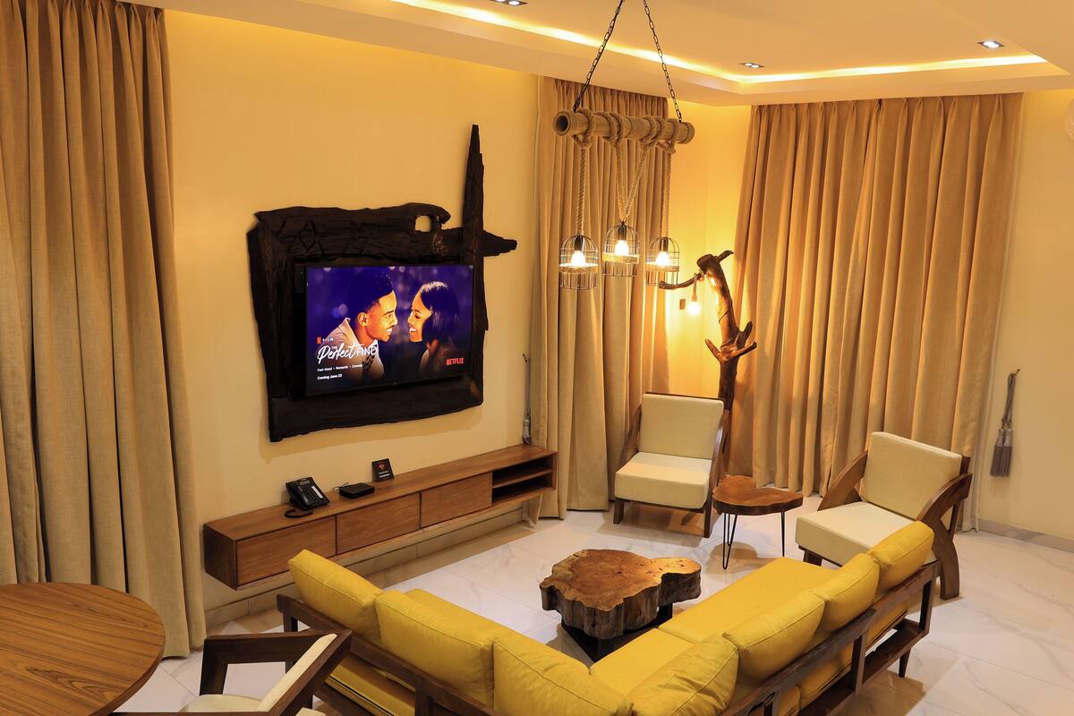 A modern living room with a television, sofa, chairs, and a coffee table.