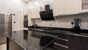 A modern kitchen with a black countertop, stainless steel appliances, and white marble backsplash. - George Residence Parkview (Lagos)