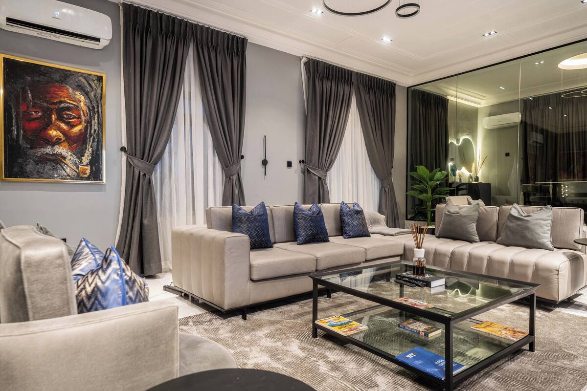 A modern living room with a beige sofa, a glass coffee table, and a large painting on the wall.